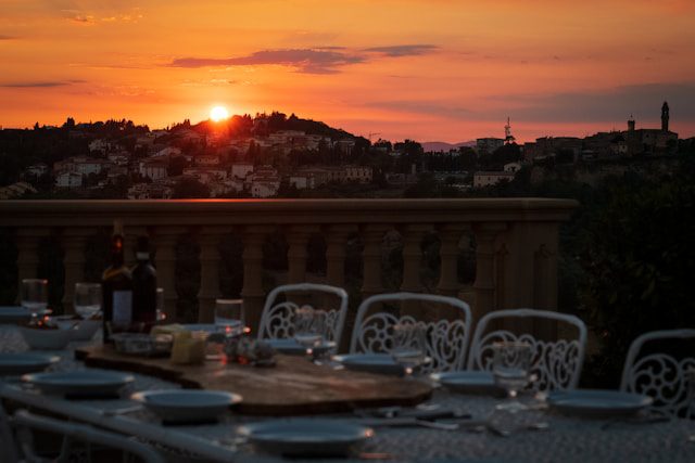 Tavolata all’aperto su terrazza panoramica con tramonto sullo sfondo