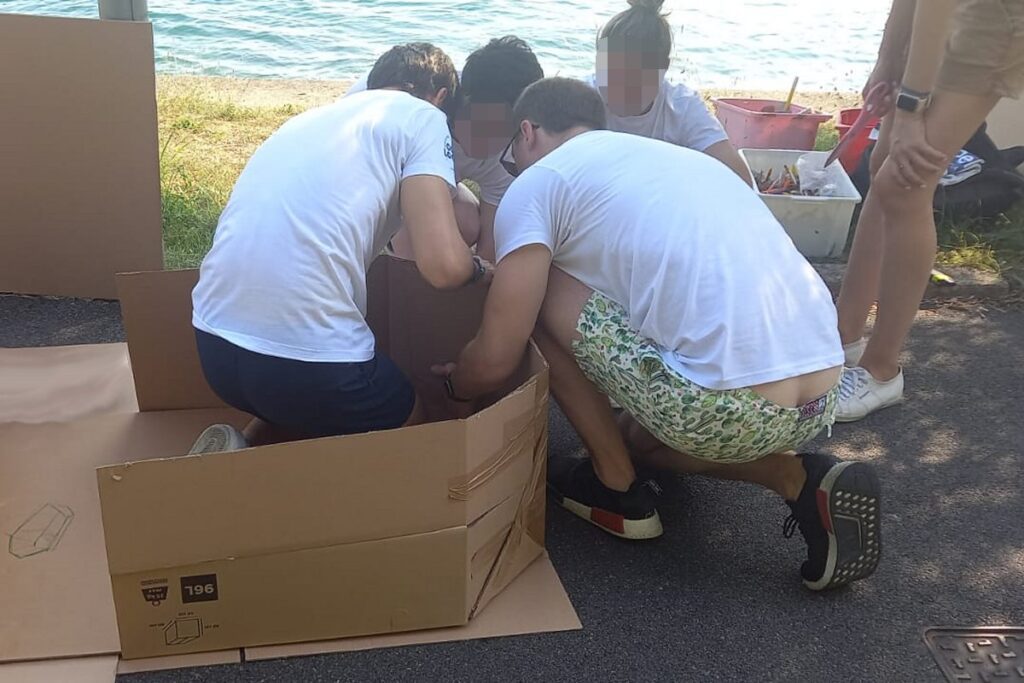 Squadra aziendale costruisce una barca in cartone per una regata di team building all'aperto