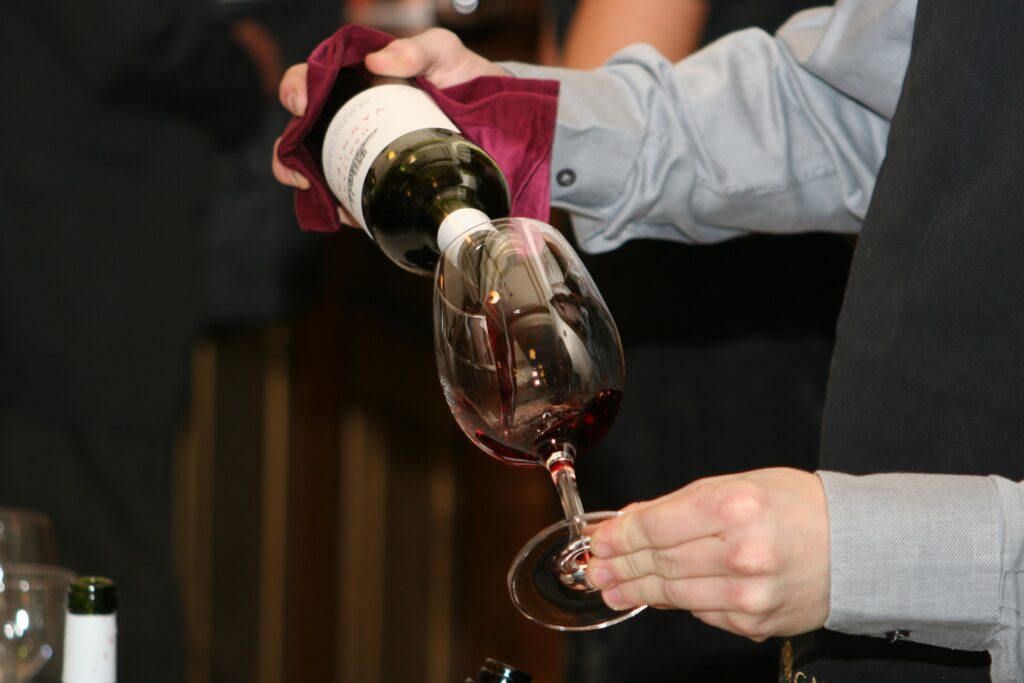 Sommelier che versa vino rosso in un calice durante degustazione